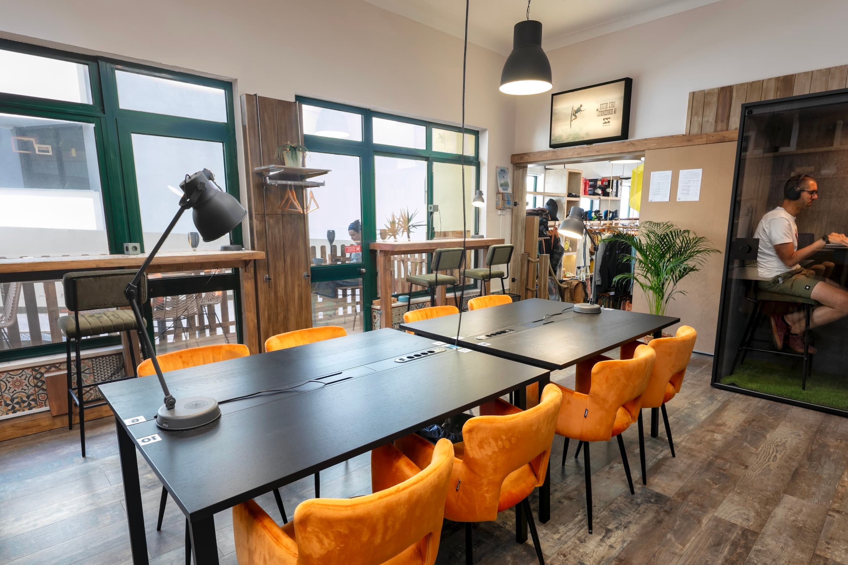 Modern coworking space with bright orange chairs and private call booth.