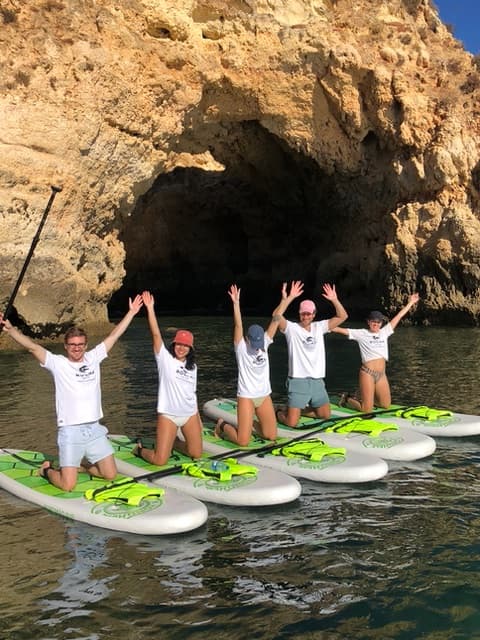 Some happy people standing on paddle boards in the water.