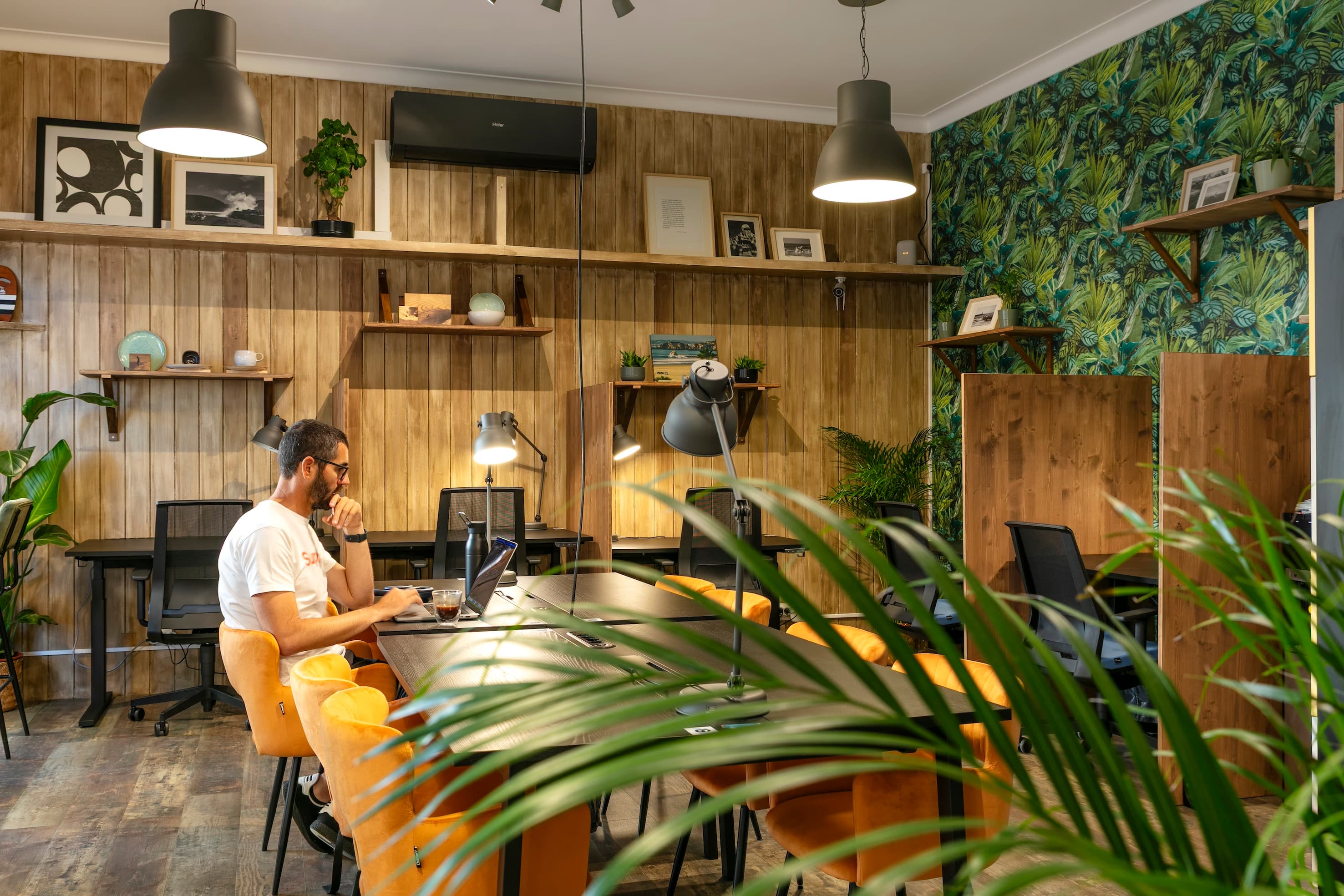 A man working on his laptop in a bright, relaxed beachside coworking space.